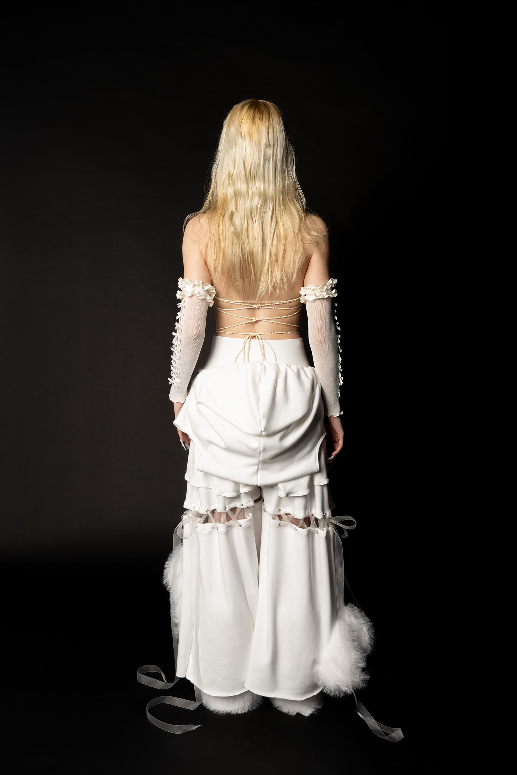 © 2026 Linh Chi Nguyen & Thanh Van Nguyen — Detailed back view of the white lace-up top and ribbon-tied cut-out trousers.